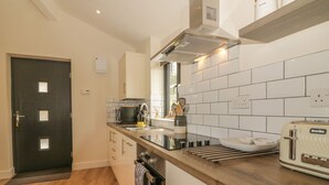 Une cuisine moderne avec une porte sombre, un dosseret de carreaux blancs, un plan de travail en bois et un grille-pain Breville.
