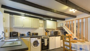 A compact kitchen with a washing machine, oven, microwave, and a dining area with a table and chairs.