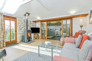 Una sala de estar con chimenea, un sofá, una mesa de centro de vidrio y una televisión.