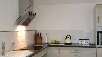 Una cocina moderna con un lavamanos de acero inoxidable, un hervidor y una repisa de vidrio sobre la encimera.