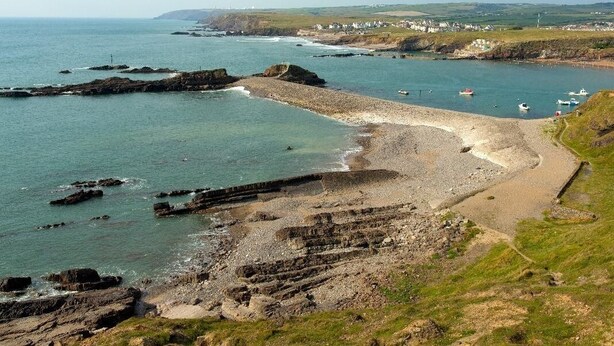 Un paisaje costero con costas rocosas, aguas tranquilas y un pueblo distante.