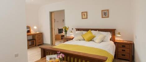 A bedroom with a bed, bedside tables, a wooden bench, and a small table with a tray of food.