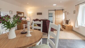 Un comedor acogedor con una mesa de madera, sillas blancas y un jarrón de flores.