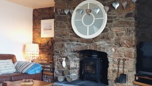 Una sala de estar acogedora con chimenea de piedra, un sofá azul y un televisor.