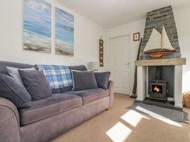 A living room with a grey sofa, a fireplace with a stone mantle, and two paintings on the wall.