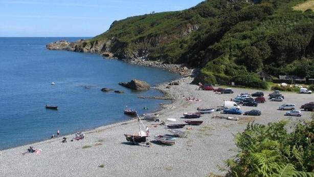 A coastal area with a pebble beach, boats, and parked cars. - Cockle Island Cottage (Helston)