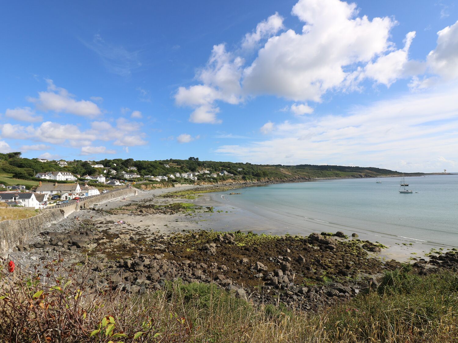 A coastal town with a rocky beach, houses along the shore, and boats in the water.