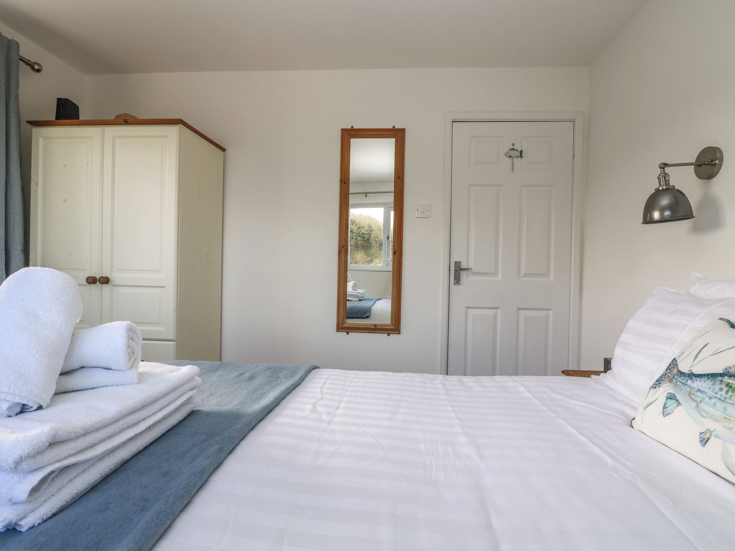 A bedroom with a bed, a wardrobe, a mirror, and a door.