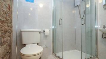 A bathroom with a toilet, a glass-enclosed shower, and a sink.