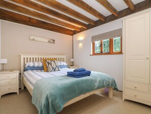 A bedroom with a bed, nightstands, a wardrobe, a window, and a wooden ceiling. - Oaklands (Camelford)