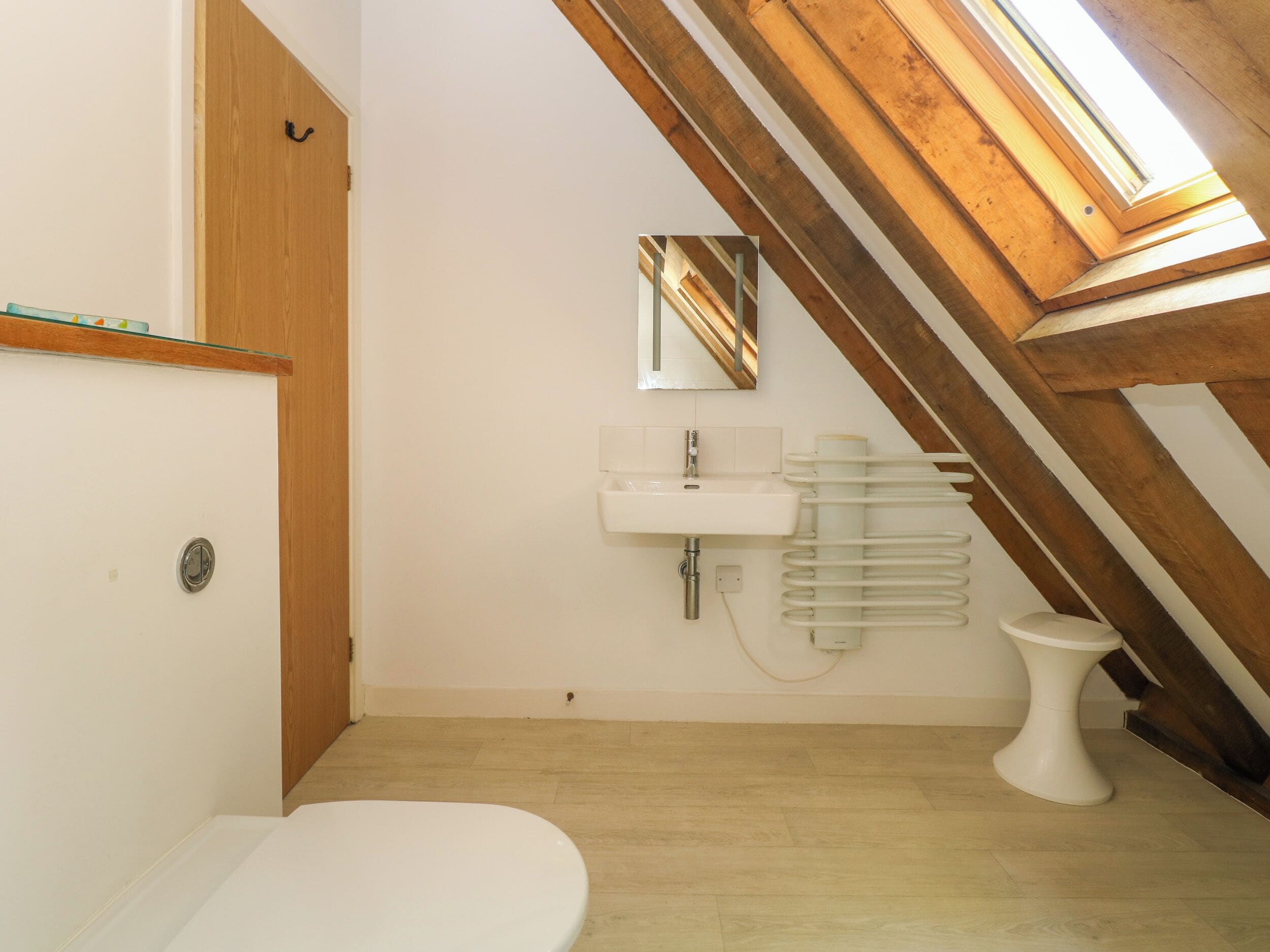 A small, modern bathroom with a skylight, a toilet, and a sink.