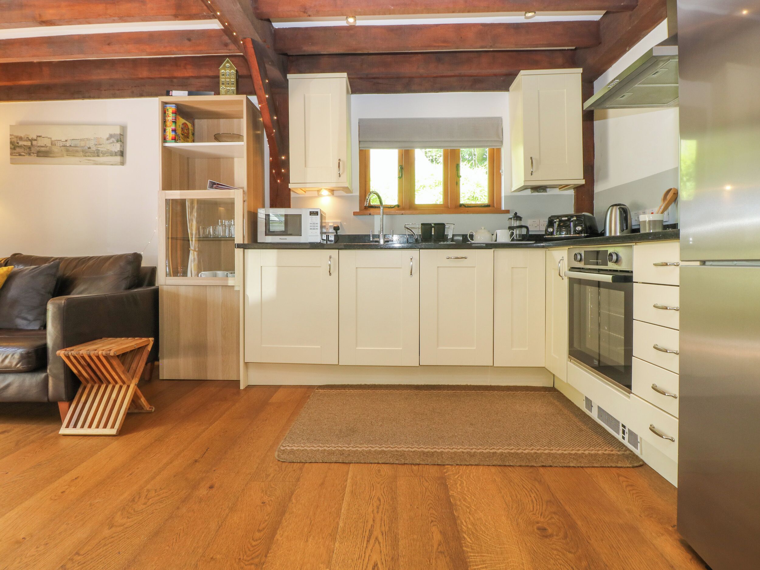 A compact kitchen with white cabinets, a built-in oven, and a refrigerator.