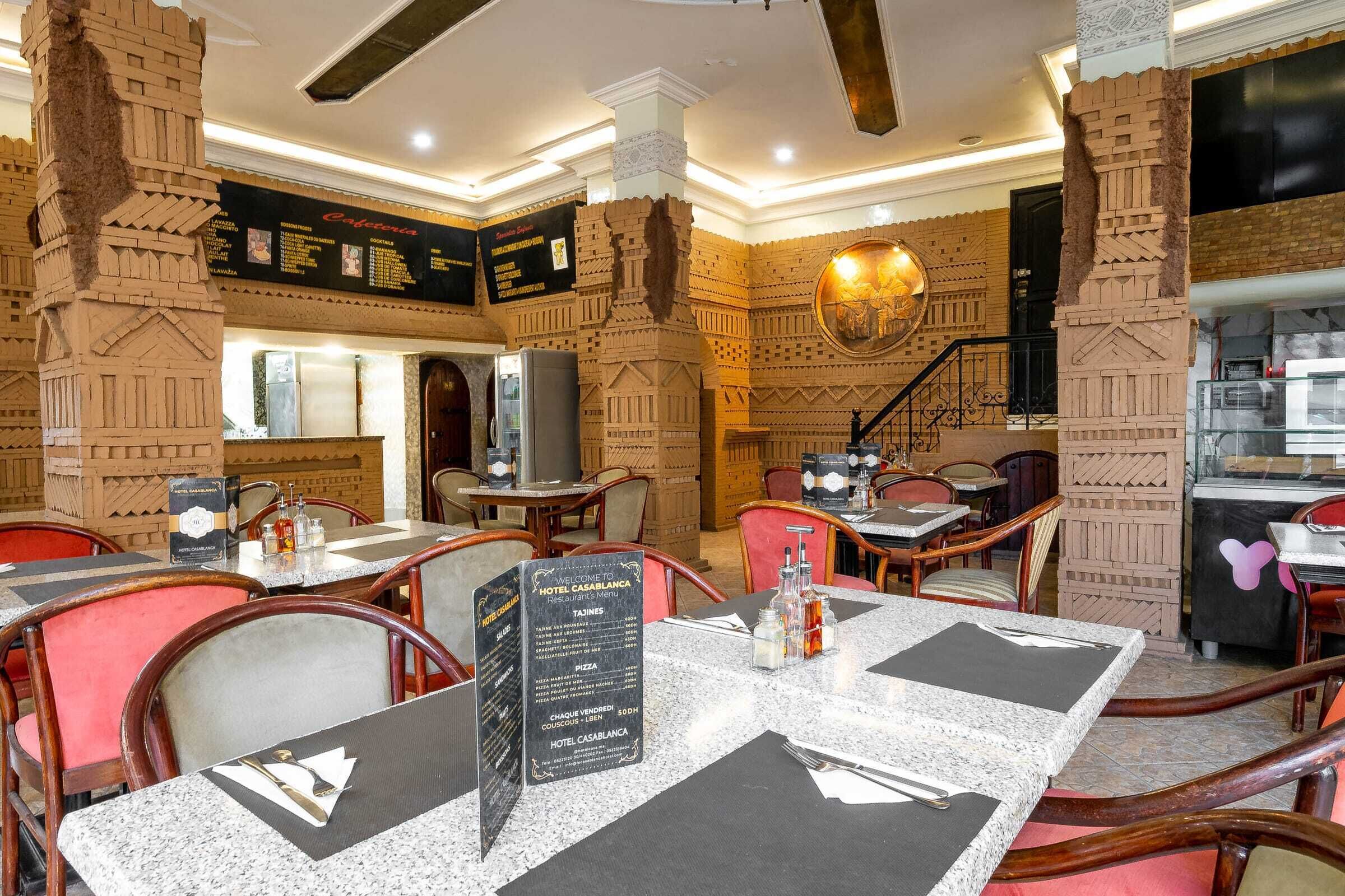 Um restaurante com colunas de tijolo, mesas de mármore e um quadro de menu.