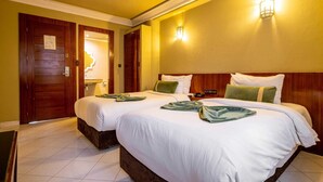 Ein Hotelzimmer mit zwei Betten, Holz-Kopfteilen und einer Wandleuchte.