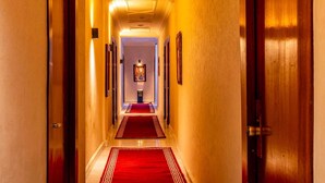 Ein Hotelgang mit roten Teppichen, Holztüren und gerahmten Bildern an den Wänden.