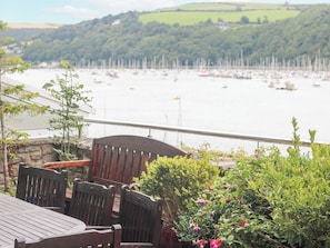 A wooden deck with chairs overlooking a marina with boats.