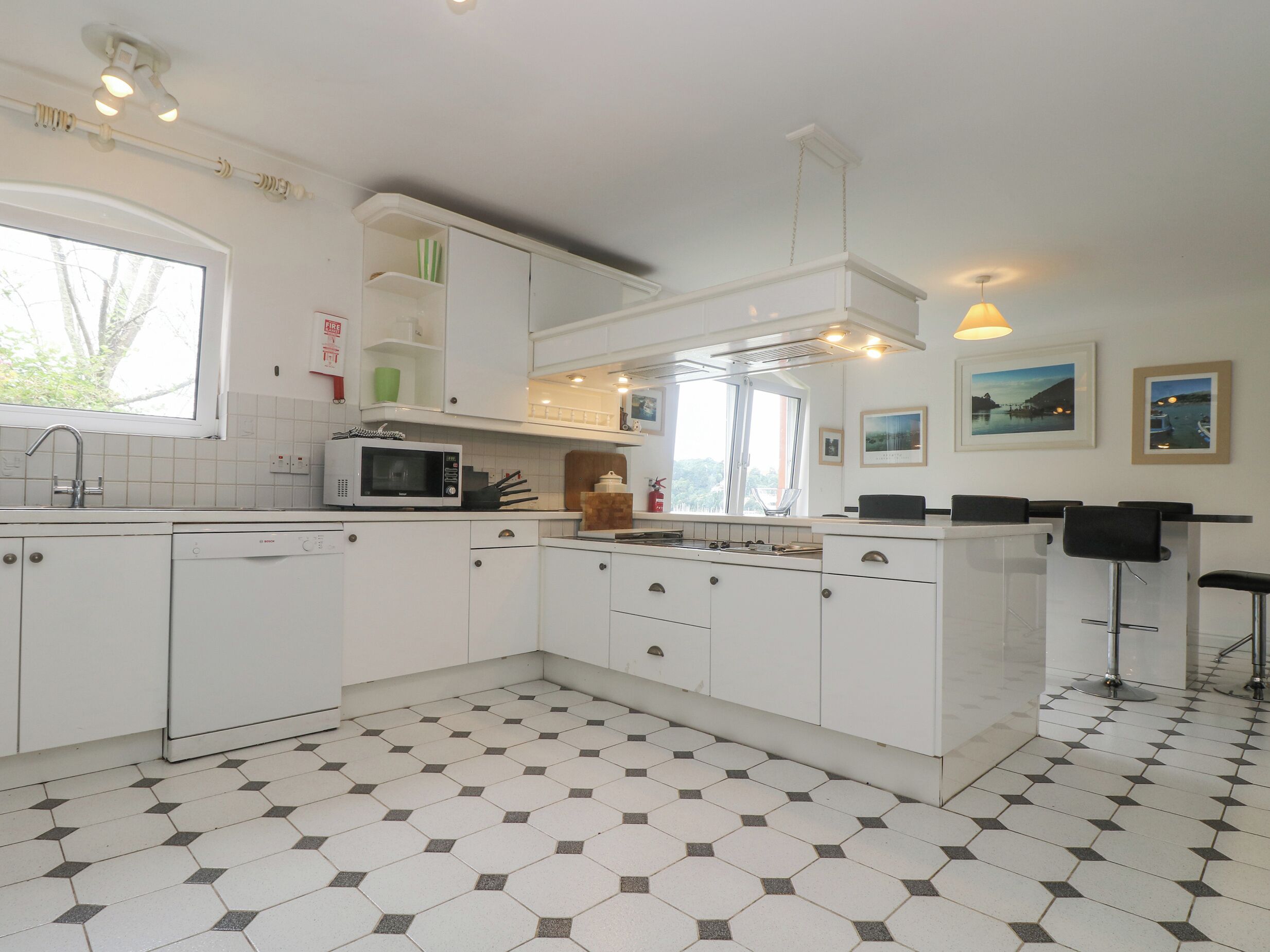A modern kitchen with white cabinets, a microwave, a sink, and a window.