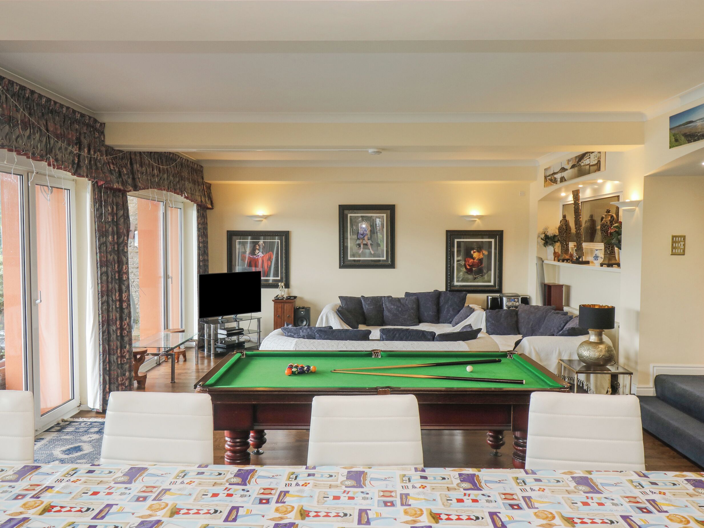 Un salon avec une table de billard, un canapé et un téléviseur.