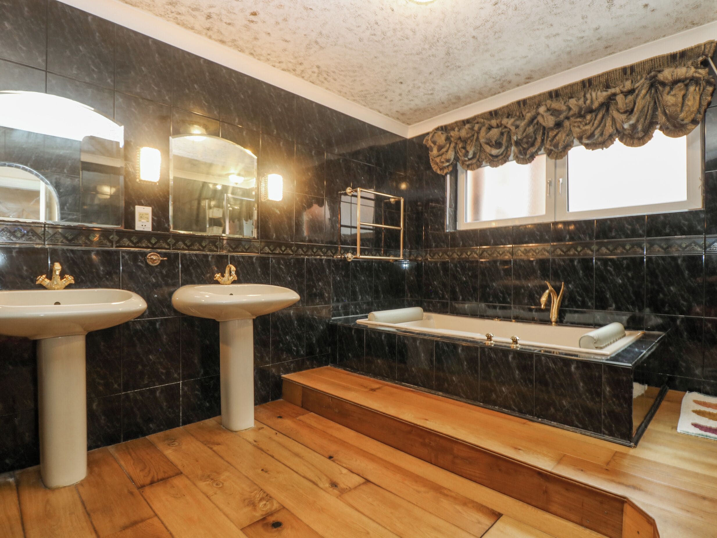 A bathroom with two sinks, a bathtub, and a vanity.