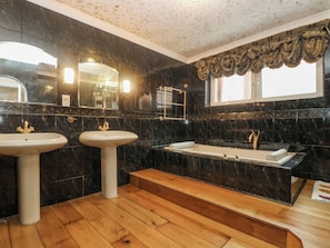 A bathroom with two sinks, a bathtub, and a vanity.