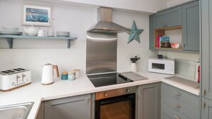 A modern kitchen with a stainless steel range hood, a microwave, a toaster, and a sink. - The Fox's Den (Whitby)