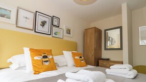 A hotel room with a bed, pillows, a wardrobe, a mirror, and framed pictures on the wall. - The Fox's Den (Whitby)
