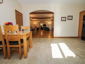 A spacious living area with a wooden dining table and chairs, a TV, and a fireplace. - The Mill House (Shrewsbury)