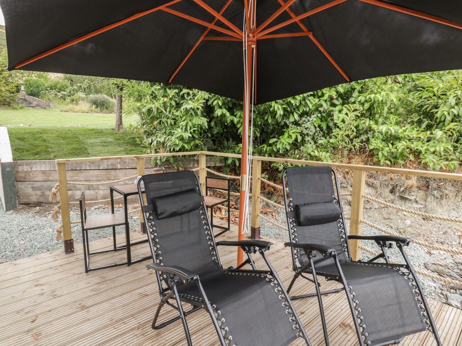 An outdoor seating area with two black lounge chairs and a large black umbrella.