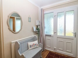 Una habitación con un banco, un espejo, una puerta con vidrio esmerilado y un pequeño calentador fijado a la pared.