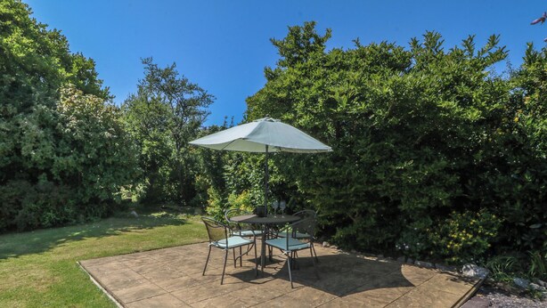 A patio with a table and chairs, surrounded by a hedge. - Salty Puffin (Tyn-y-Gongl)