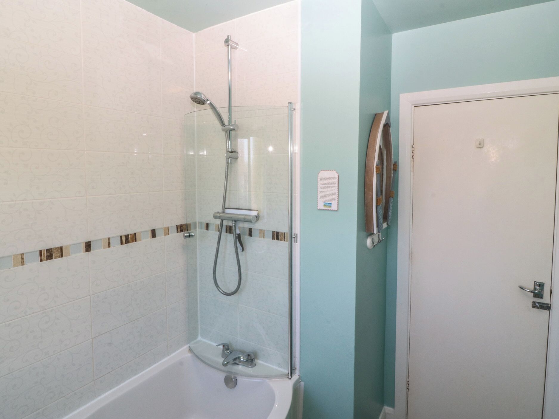 A bathroom with a glass-enclosed shower, a white bathtub, and a door with a handle.