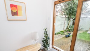A room with a wooden table, a lamp, a colorful rug, and a door leading to a garden. - 24 College Lane (Stratford-upon-Avon)