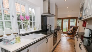 A modern kitchen with white cabinets, a black countertop, and a wooden floor. - 24 College Lane (Stratford-upon-Avon)