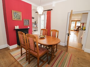 Une salle à manger avec une table et des chaises en bois, une cheminée et une bibliothèque.