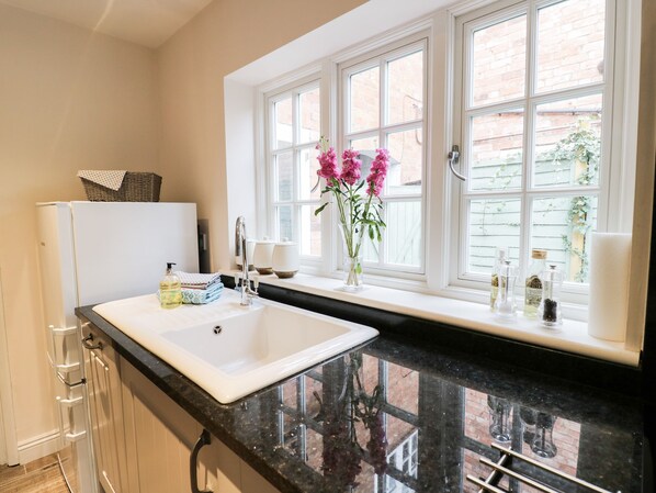 A kitchen with a white sink, black countertop, and a window with a view of a brick building.