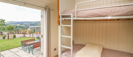 Habitación con literas y vista a un espacio verde y un edificio a lo lejos.