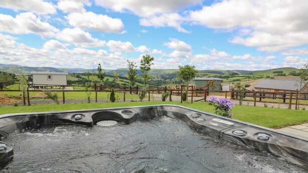 A hot tub with a view of a fenced property and hills in the background. - Hillside View (Rhayader)