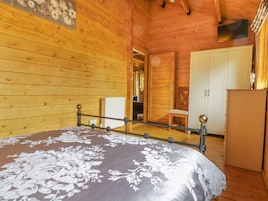 Un dormitorio de cabaña de madera con una cama, un armario y una pequeña mesa.