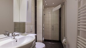 A modern bathroom with a large white sink, a toilet, and a glass-enclosed shower area. - Hotel am Rosenplatz 24-hour check-in, free parking, guest kitchen (Rühen)