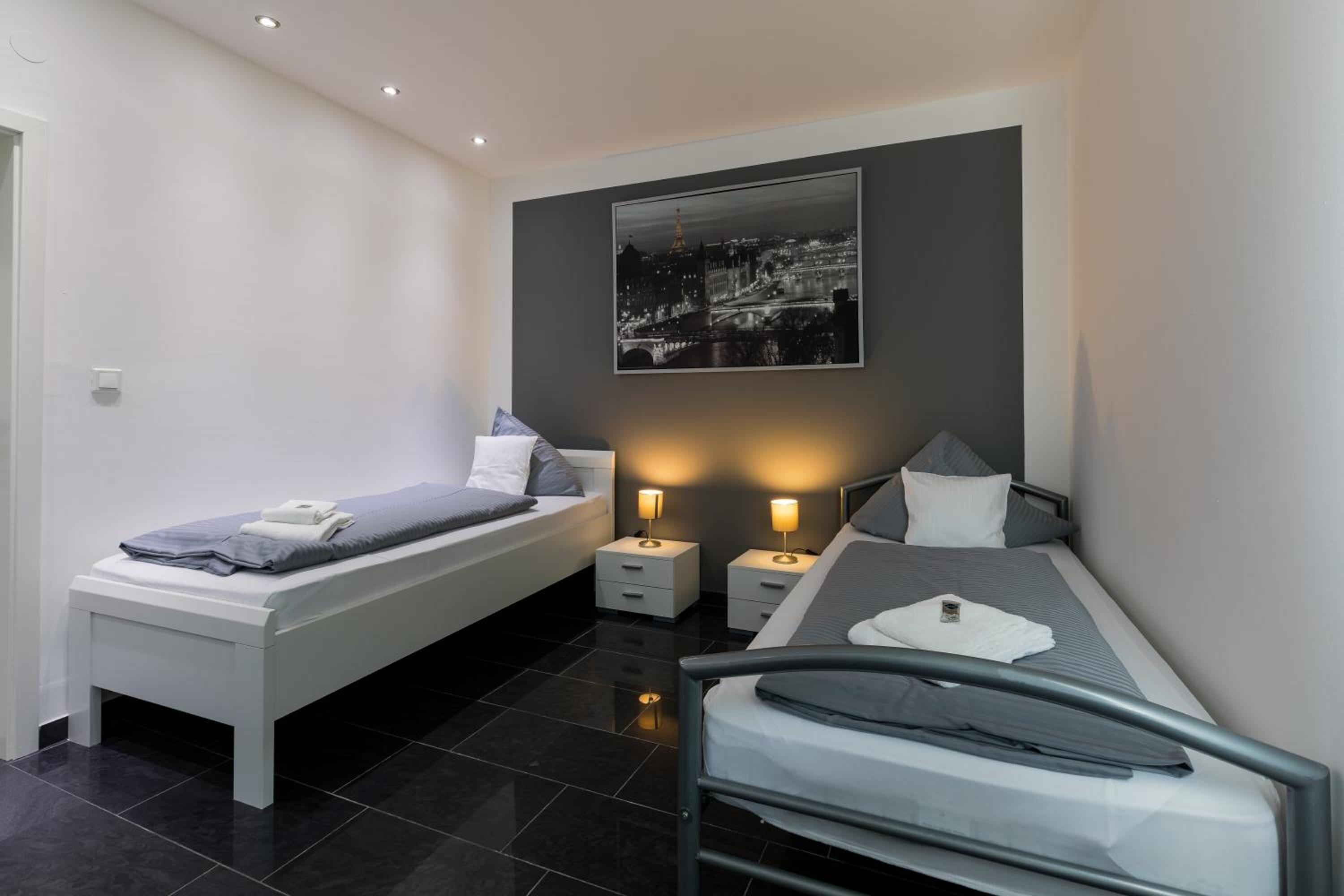 Um quarto moderno com cama, mesas de cabeceira e um criado-mudo.