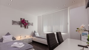 A modern hotel room with a bed, bedside tables, a desk, and a window with blinds. - Hotel am Rosenplatz 24-hour check-in, free parking, guest kitchen (Rühen)