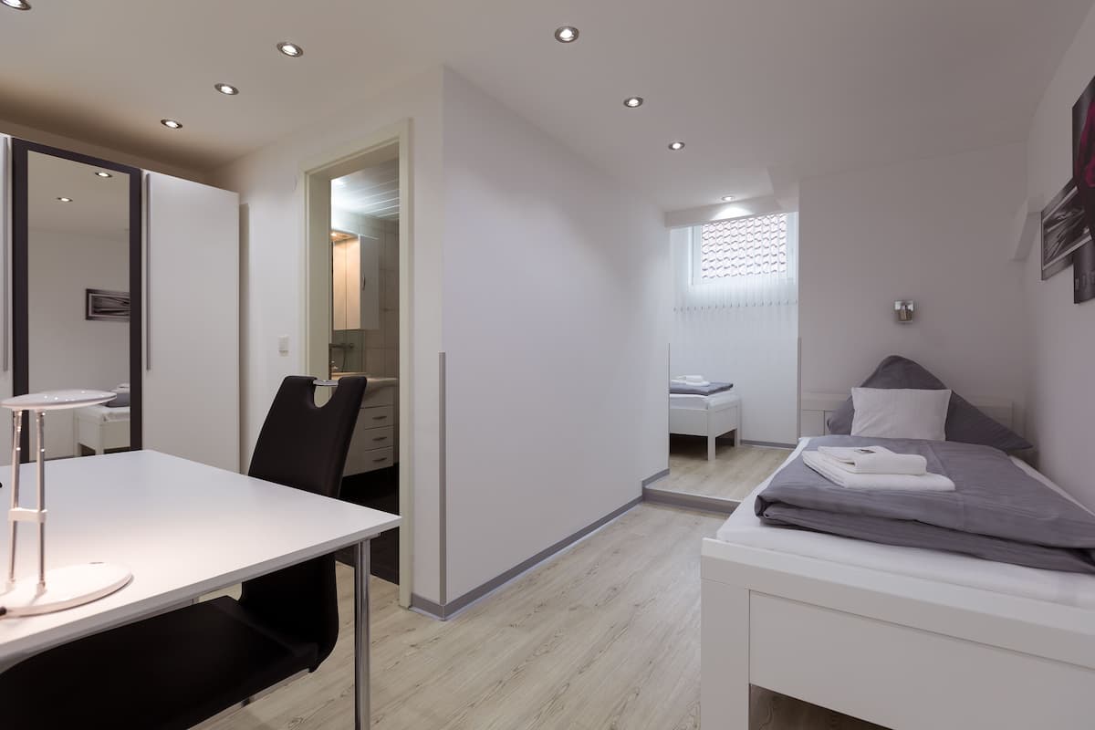 Une chambre moderne et compacte, équipée d’un lit, d’un bureau et d’une chaise.