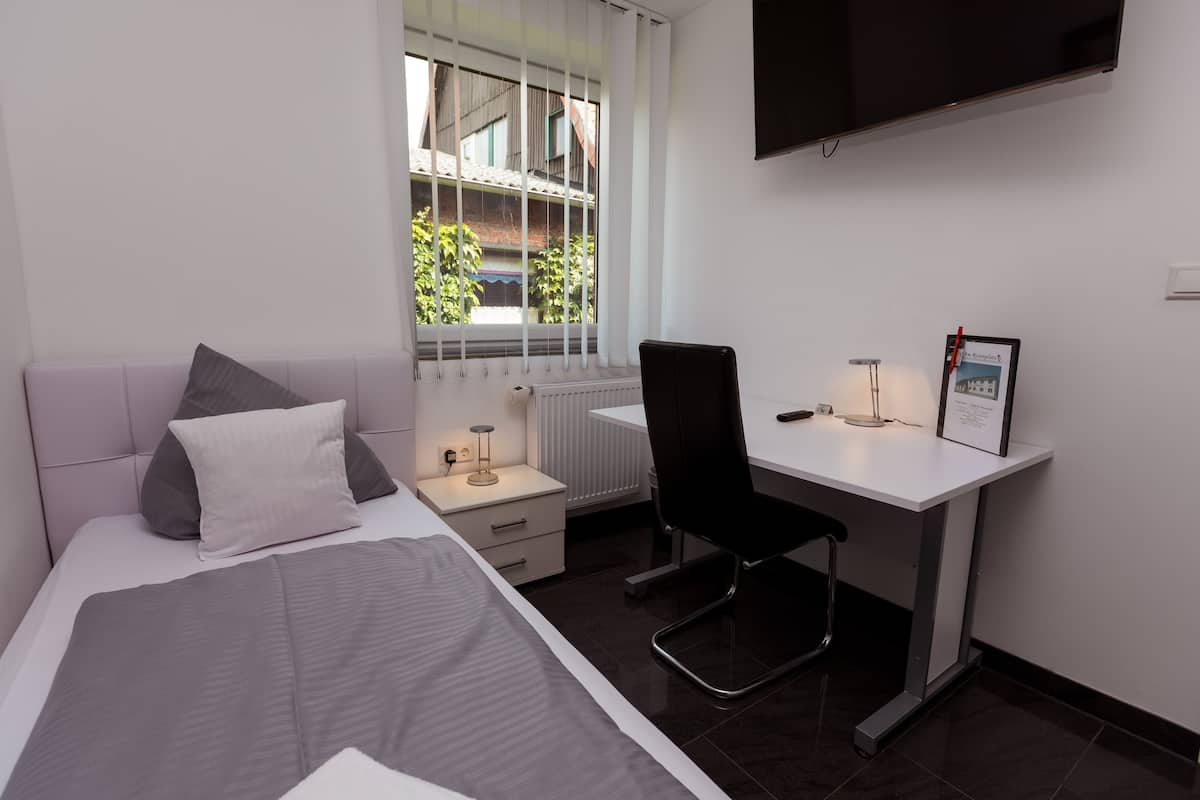 Une chambre à coucher moderne, comprenant un lit, une table de chevet, un bureau, une chaise et un téléviseur fixé au mur.