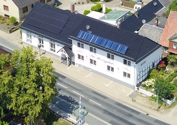 Vista aérea de um hotel com telhado escuro, painéis solares e uma placa com a inscrição 'Hotel Rosenthal'.