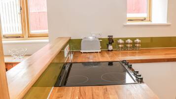 A kitchen with a black stove, wooden countertops, a toaster, and jars labeled tea, coffee, and sugar.