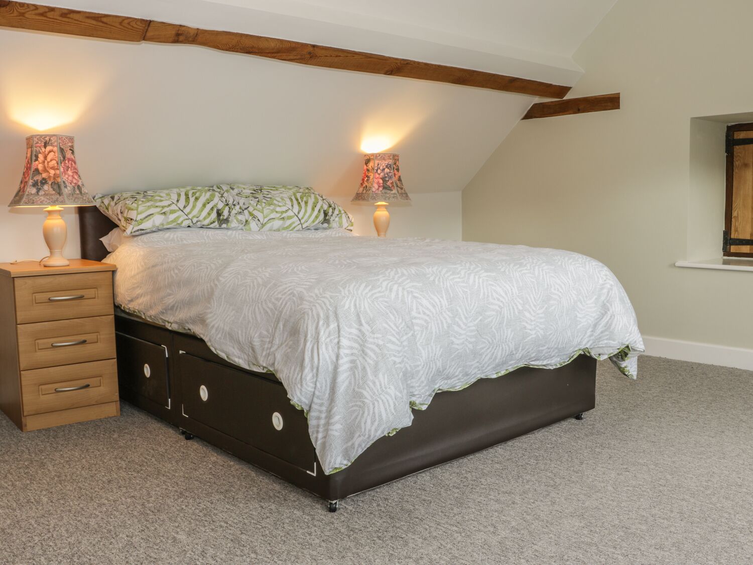 A bedroom with a bed, two bedside lamps, a nightstand, and a dresser.