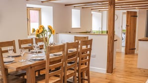 Un coin repas avec une table en bois dressée pour six personnes, entourée de chaises en bois.