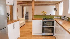 Une cuisine moderne avec des poutres en bois, une cuisinière en acier inoxydable, des armoires blanches et un plan de travail en bois.