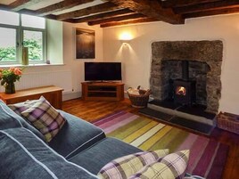 A cozy living room with a stone fireplace, a television, and a sofa with plaid cushions.
