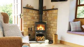 A cozy living room with a stone fireplace, a comfortable sofa, and a television mounted on the wall. - Sunnybrook Cottage (Clitheroe)